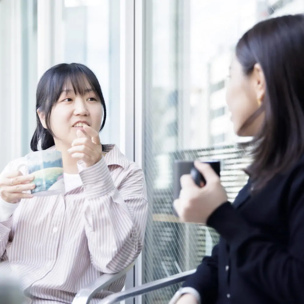 社内の女性二人がベランダで話している様子