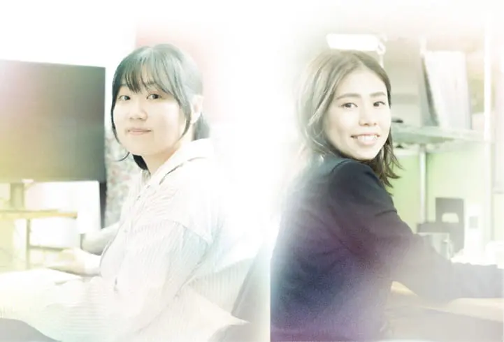 社員の女性2人が背中合わせに座ってこちらを見ている様子